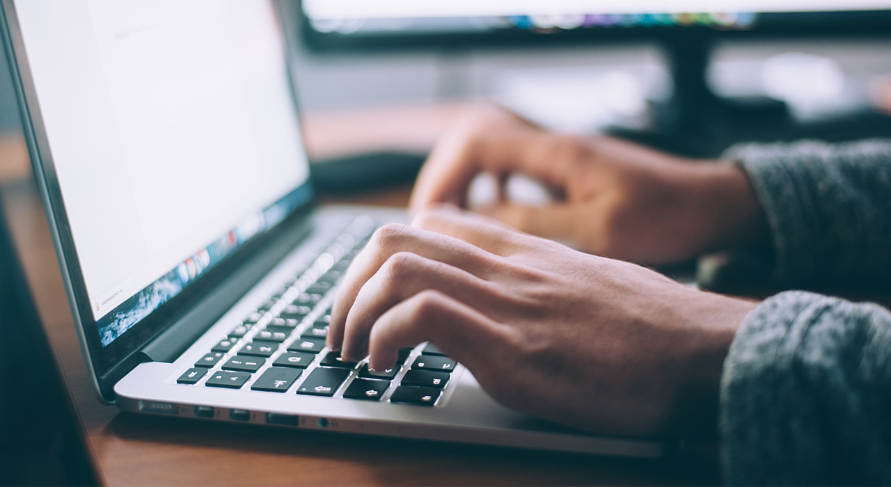 Hands writing on a computer