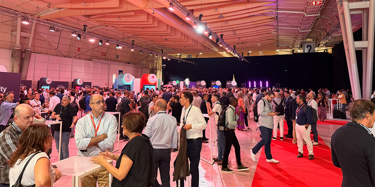 Profissionais de tecnologia em networking numa área de exposição durante um evento de cibersegurança