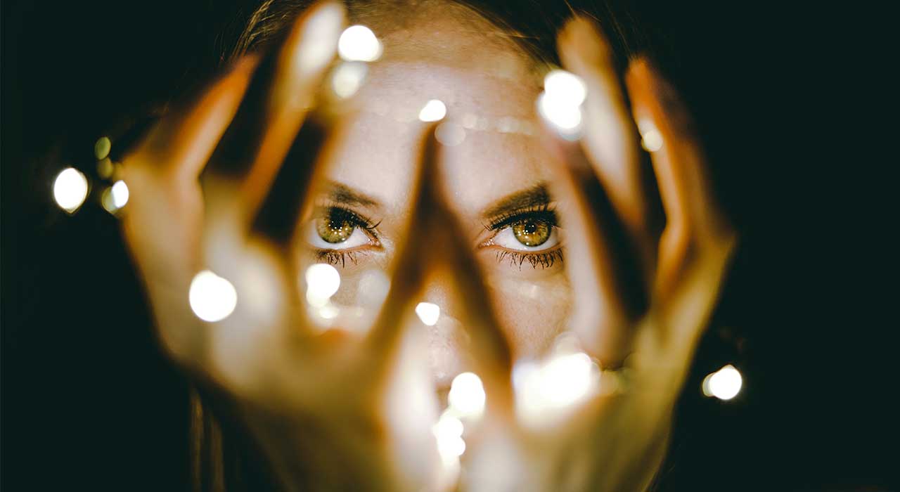 Woman looking through her hands with lights represents the discovery of Trends 