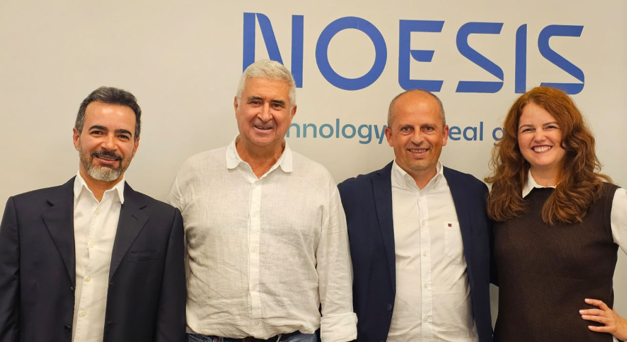 Four people posing together in front of a Noesis backdrop, including CEO Alexandre Rosa in a white shirt